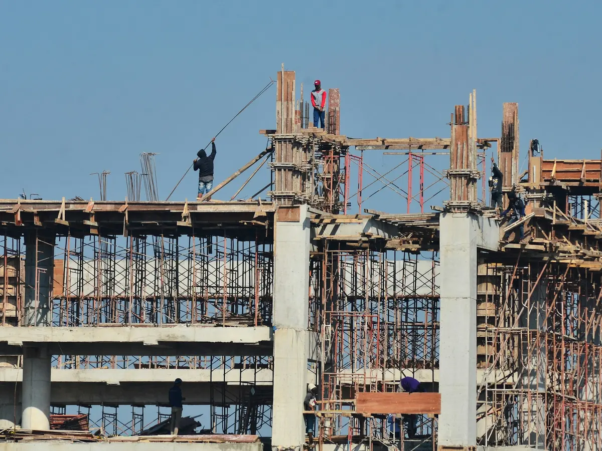 Operários executando a estrutura de concreto de um edifício com escoramentos