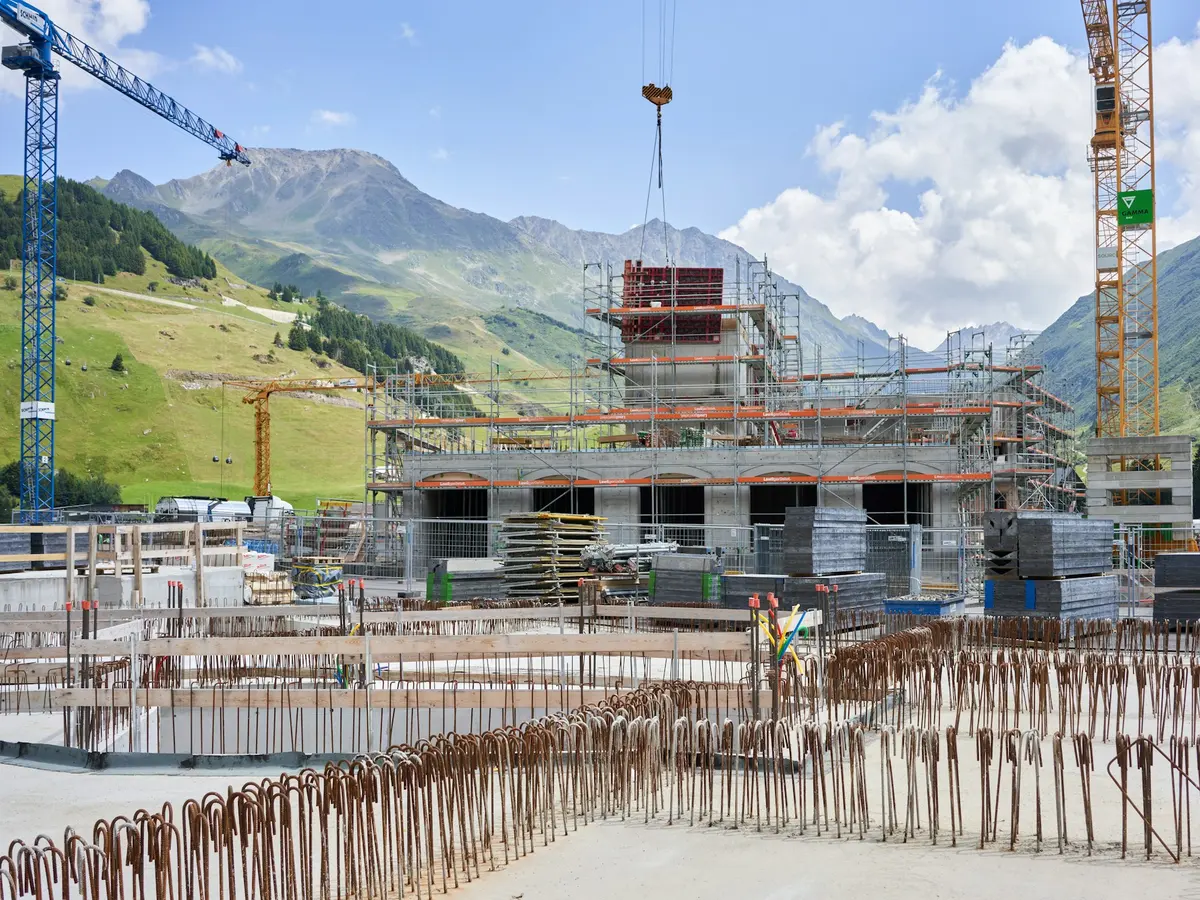 Canteiro de obras com armaduras de fundação e guindaste ao fundo