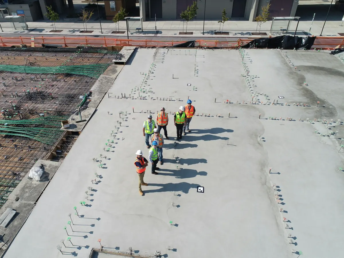 Vista aérea de equipe de obra caminhando sobre laje de concreto recém-executada